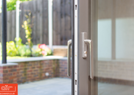 Close-up-of-an-air-lift-and-slide-door-hande-leading-into-a-Bushey-garden